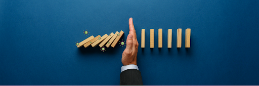 hand stopping the falling of dominoes