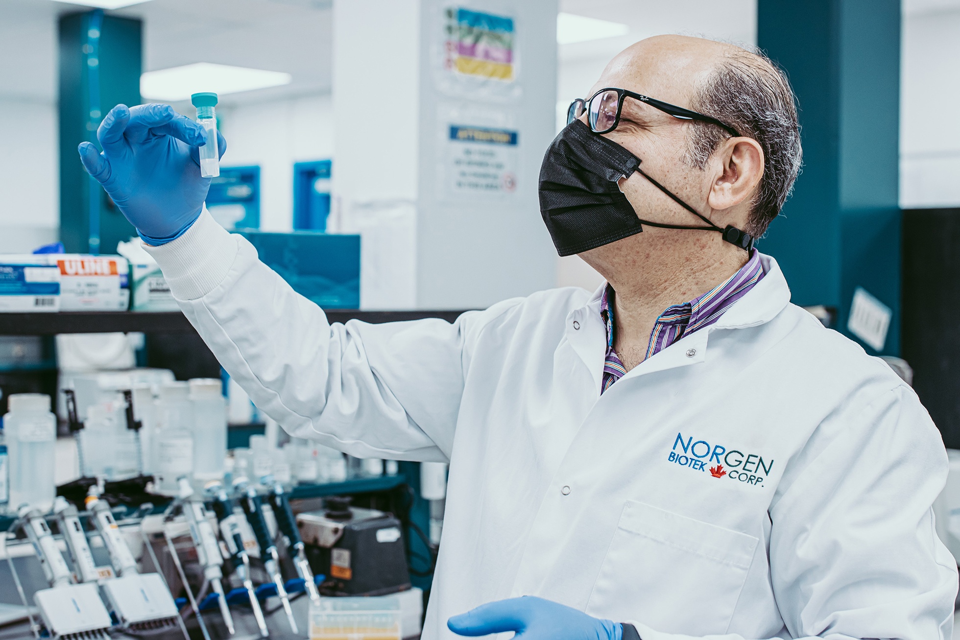 Norgen scientist wearing PPE observing saliva sample